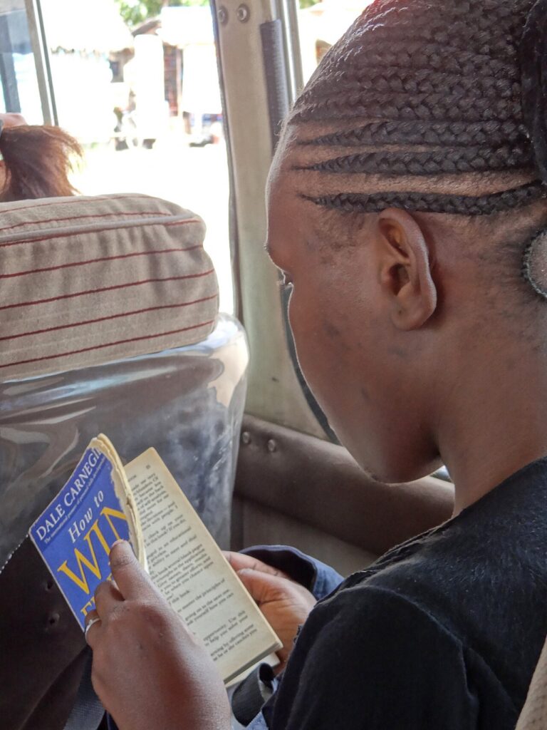 Passageira lê o livro de Dale Carnegie num ônibus na Tanzânia