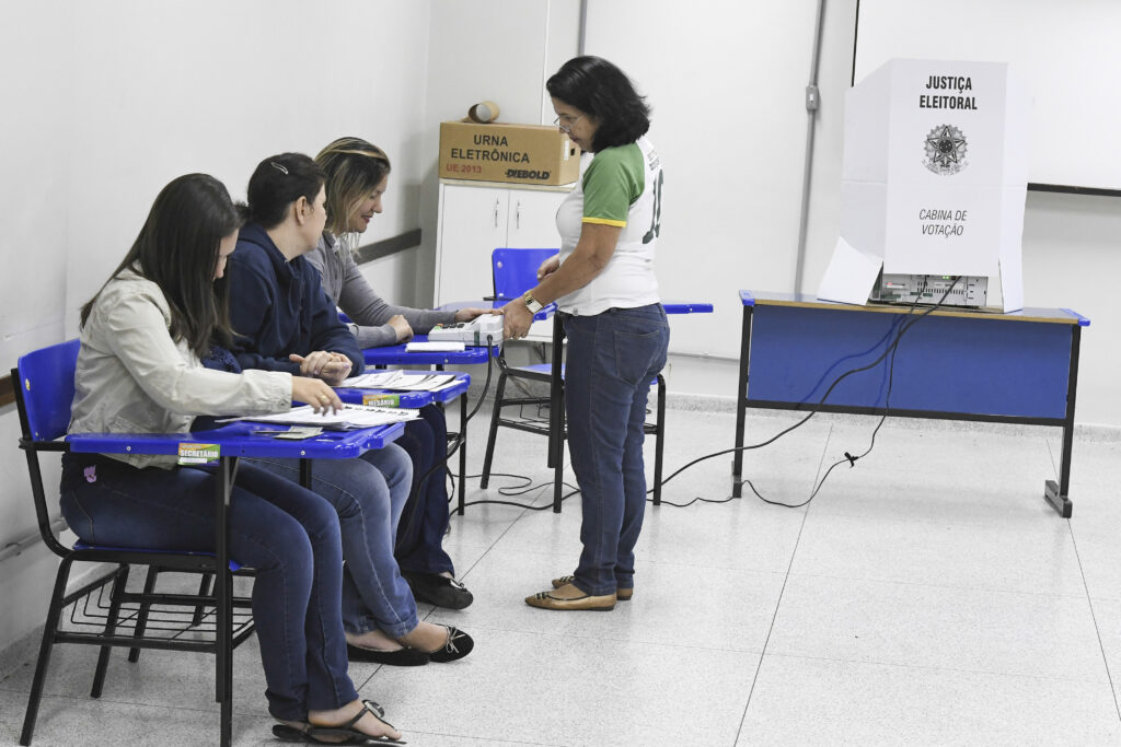 Mesários atendem eleitora em seção eleitoral; o segundo turno dos governadores será em 25 de outubro