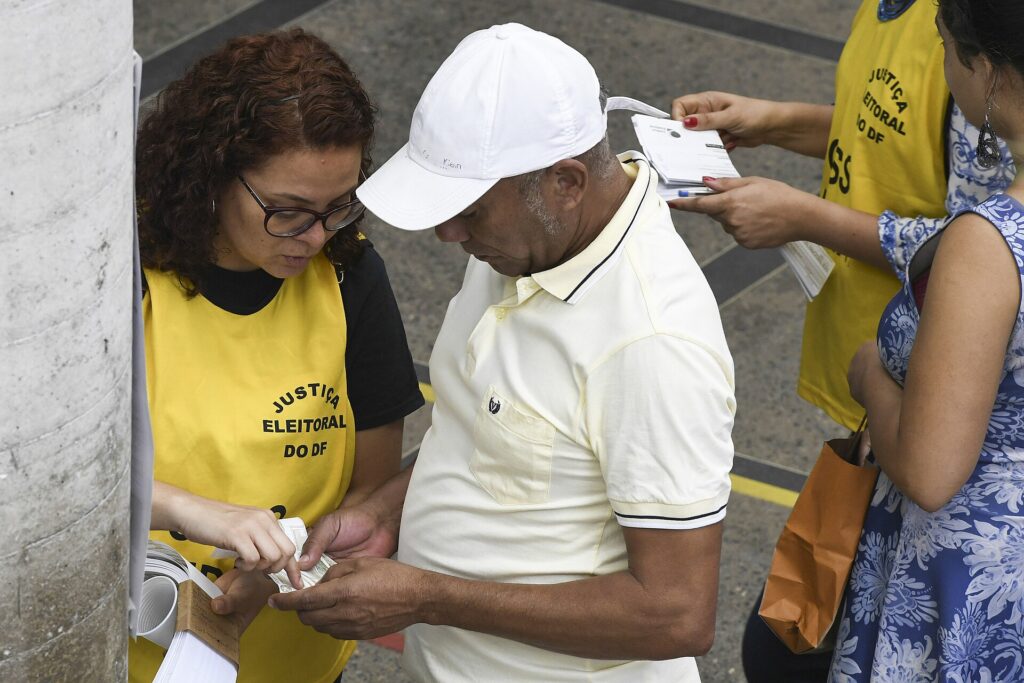 Voluntária da Justiça Eleitoral orienta eleitores: justificar o voto evita pendência e multa